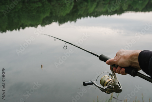 Fishing for pike, and perch from a lake or pond. Background wild nature. Fisherman with rod, spinning reel on the river bank. Wild nature. The concept of a rural getaway. Article about fishing day.
