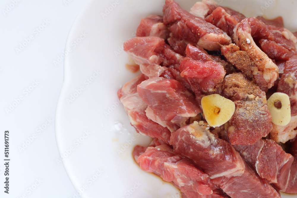 Seasoning cut beef steak, garlic and pepper on plate
