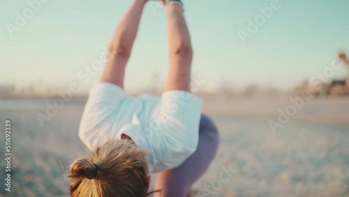 Young woman in sportswear stretching preparing her body for yoga on the beach. Female yogi looking confident practicing outdoors