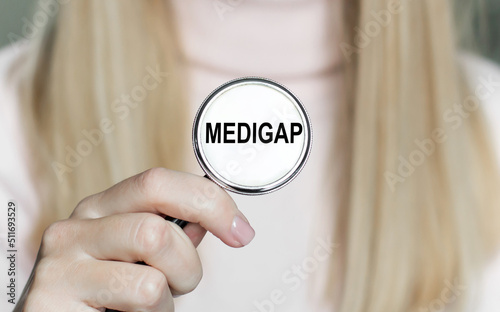 MEDIGAP inscription on the stethoscope in the hands of a girl photo