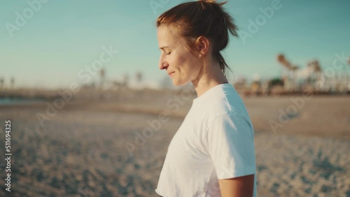 Beautiful blond woman feeling good after yoga practice on the beach. Sporty girl walking by the sea after workout