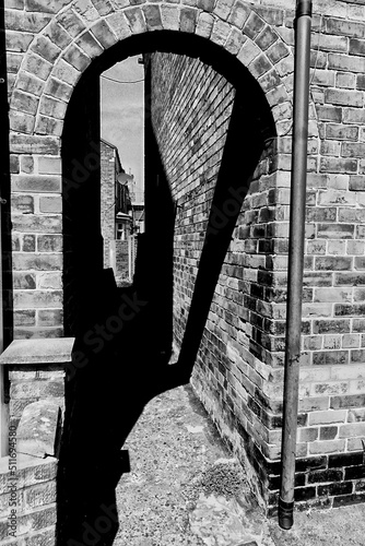 Black and white image of a shady archway alley photo