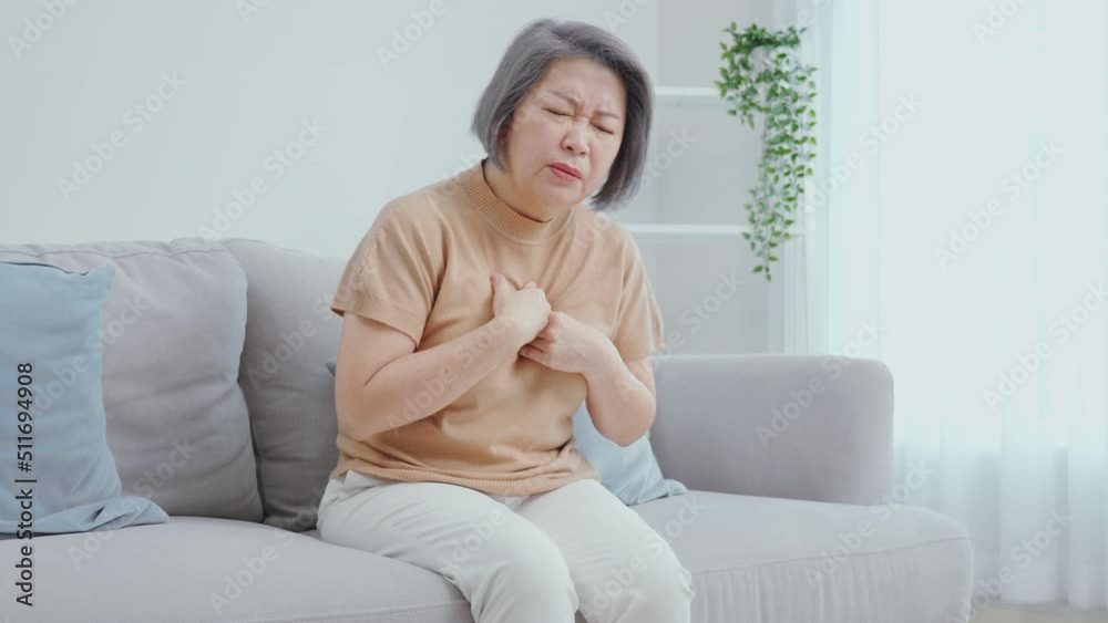 An older woman with short hair was sitting on the sofa and was chest pain from painful chest pain from a chronic disease. An older woman with short hair was sitting on the sofa and was chest pain from painful chest pain from a chronic disease.