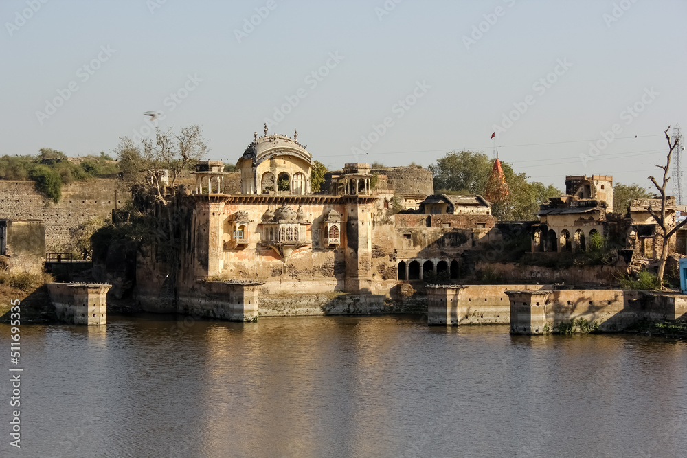 The exterior facade of the ancient royal palace rising above the waters of a lake in the town of Deeg in Rajasthan, India.