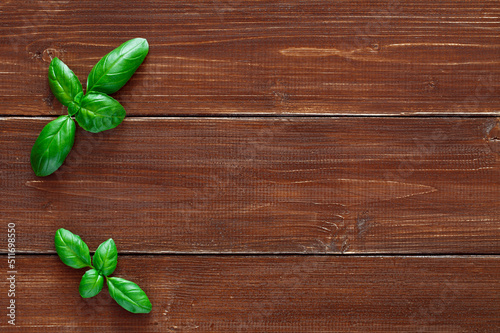 Basil, green leaves on wooden brown plank table top background, top view, space to copy text..