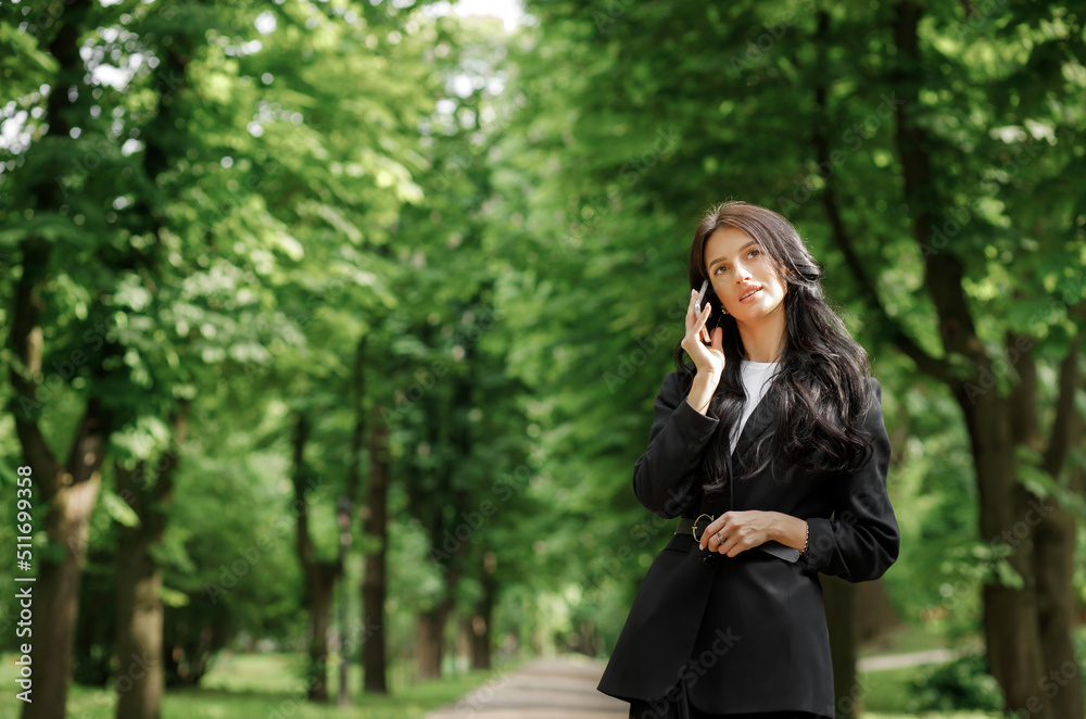 Business woman use cellphone outdoors. Beautiful focused young girl wearing a formal suit Business woman use cellphone outdoors. Beautiful focused young girl wearing a formal suit