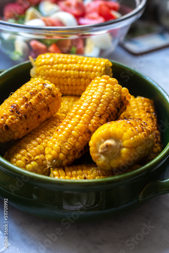 Grilled sweet corn cobs in a green ceramic bowl