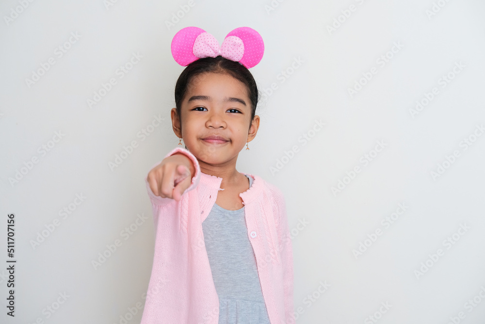 Asian little girl looking to the camera while smiling and pointing forward Asian little girl looking to the camera while smiling and pointing forward