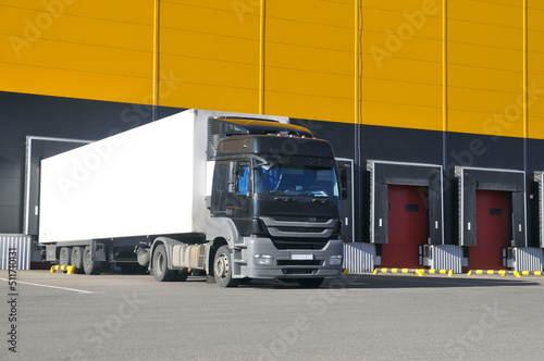 Unloading trucks in a modern warehouse complex. Transportation, storage.