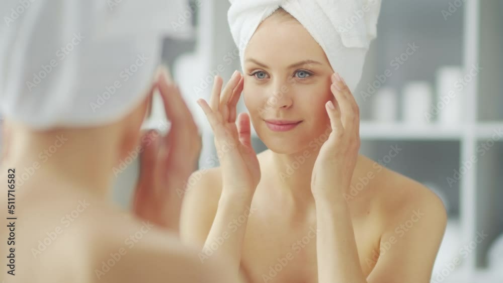 Young Girl is Sitting in front of a Make-up Mirror in the Bathroom and Applying a Skin Cream. Beautiful Woman is Making Cosmetic Rejuvenation Procedures. Health and Beauty Concept. Young Girl is Sitting in front of a Make-up Mirror in the Bathroom and Applying a Skin Cream. Beautiful Woman is Making Cosmetic Rejuvenation Procedures. Health and Beauty Concept.