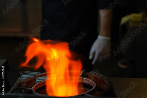 blazing flame in the blur with the light on the stove. photo inside. gas.