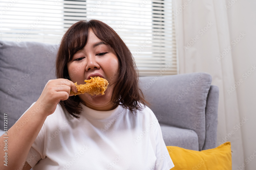 Young Asian oversize women gain weight while eating fried chicken, potato chips and French fried. Junk food that can cause obesity and unhealthy for human body. Young Asian oversize women gain weight while eating fried chicken, potato chips and French fried. Junk food that can cause obesity and unhealthy for human body.