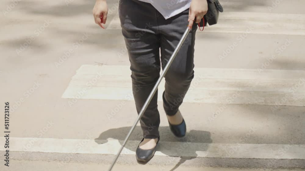 Woman with blindness disability crossing street walking on crosswalk