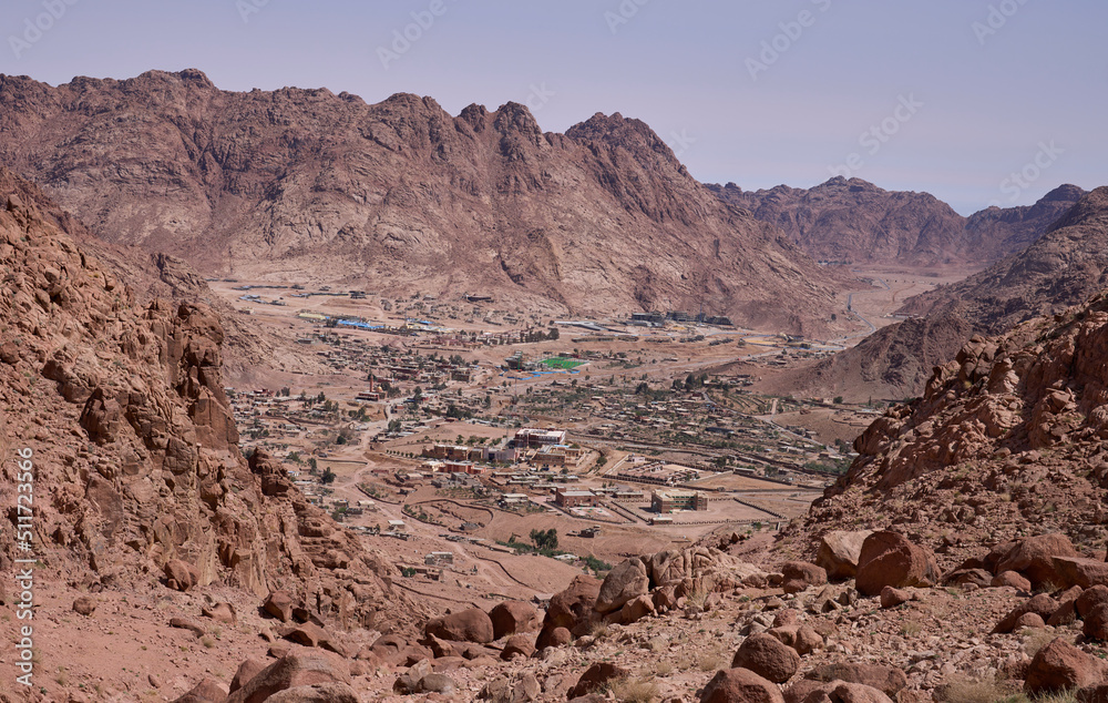 Saint Catherine, Egypt - panoramic view of the city downtown from Abu Jeefa pass on the sunny morning. The city is UNESCO world heritage site. Red mountains at the background.
