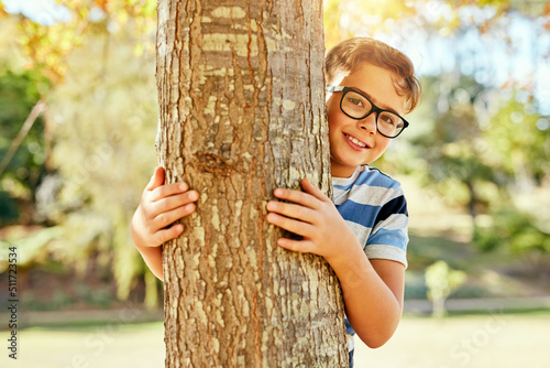 I think Ive found a pretty good hiding spot. Portrait of a little boy playing at the park.