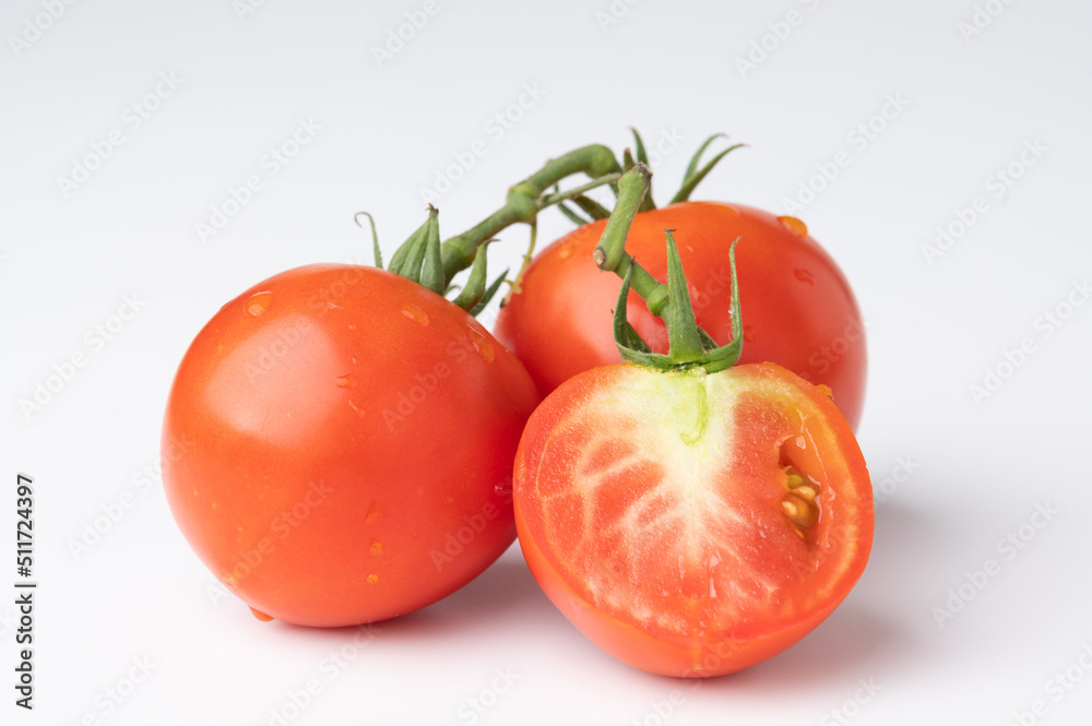 Fresh tomatoes on a green stem on white Fresh tomatoes on a green stem on white