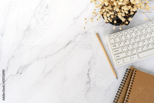 Flat lay office desk with computer keyboard, pencil, flower and note pas with copy space photo