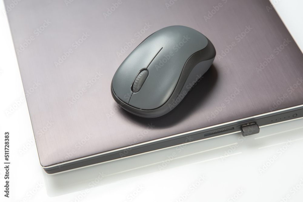 Computer wireless mouse next to a laptop on a white table close-up. electronic personal industry Computer wireless mouse next to a laptop on a white table close-up. electronic personal industry