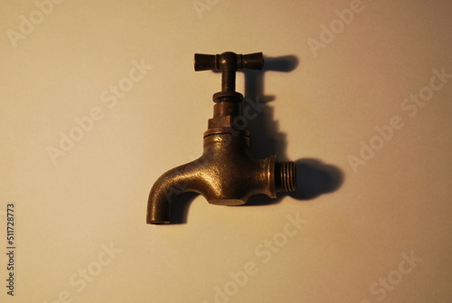 antique object - faucet - made of brass on a light background, under warm artificial lighting