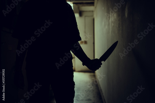 The shadow of a female murderer stood terrifyingly holding a knife and lit from behind.Scary horror or thriller movie mood or nightmare at night Murder or homicide concept. photo