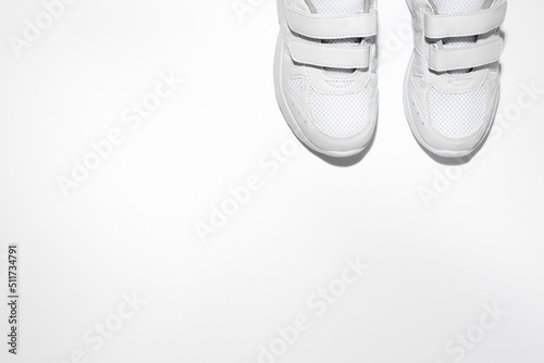 mock up flat lay two white women's sneakers with velcro fasteners with copy space isolated on a white background.