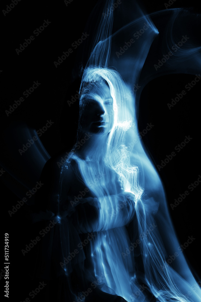 Abstract woman silhouette in light trails of light painting with blue ...