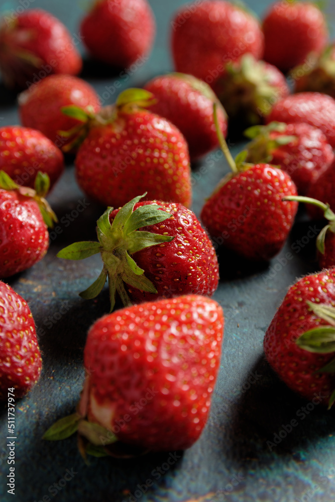 Close up of strawberries scattered on a green background Close up of strawberries scattered on a green background