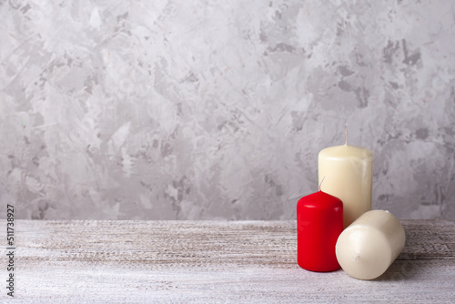 three candles on a wooden table on a gray concrete background, copy space for text.