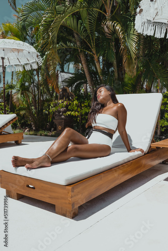 young Indonesian girl relaxing on white sunbed lounger in bikini swimsuit