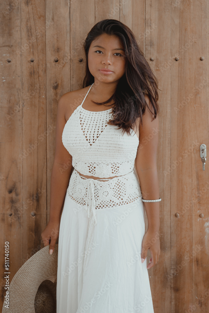Fototapeta premium young serious Indonesian woman in white maxi dress with hat in hand