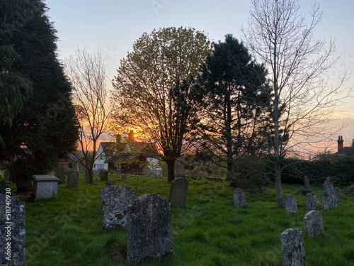 Traditiona Englich old church graveyard in the evening, sundset behind the trees, end of the day, concept for end of life, melanconia, red sunset in spring in the UK photo