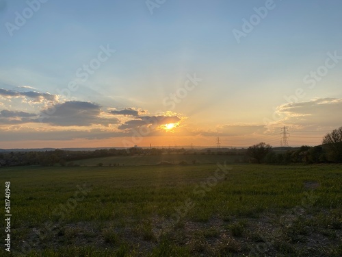 Sunset over the field in England, red sunset behind the cloud in spring time, romantic view