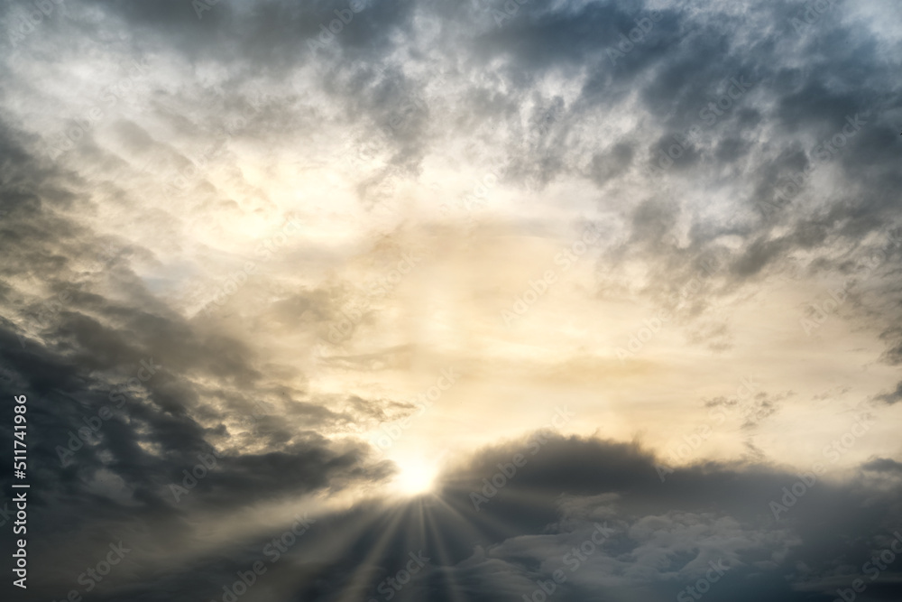 Fototapeta premium sun rays break through the dense storm clouds in the evening sky