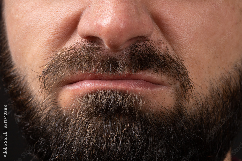 emotion of disgust, hatred close-up on face and lips of young unrecognizable man with black beard and mustache, concept of rage and anger. emotion of disgust, hatred close-up on face and lips of young unrecognizable man with black beard and mustache, concept of rage and anger.