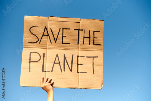 A Cardboard Signs saying Save the Planet held by two hands on sky background