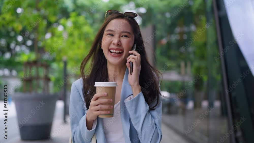 Asian female casual relax digital nomad freelance expat programer smart casual cloth walking on sidewalk urban city with holding smartphone smiling cheerful positive feeling downshifting lifestyle Asian female casual relax digital nomad freelance expat programer smart casual cloth walking on sidewalk urban city with holding smartphone smiling cheerful positive feeling downshifting lifestyle