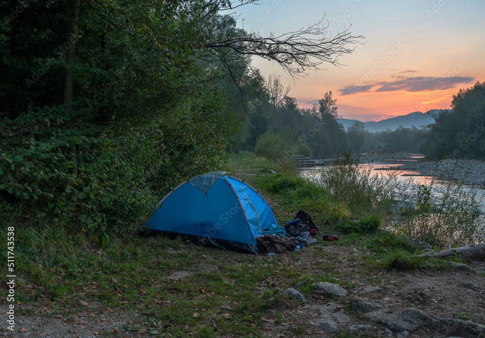 Camping in a tent by the river at sunset