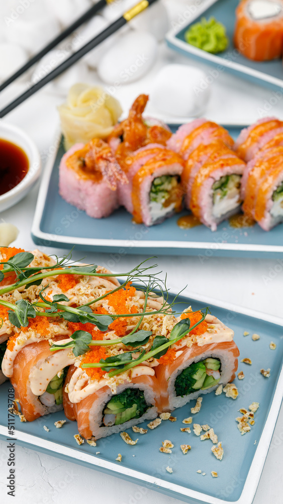 Japanese cuisine. Rolls with salmon on a white table.
Japanese cuisine. Rolls with salmon on a white table.