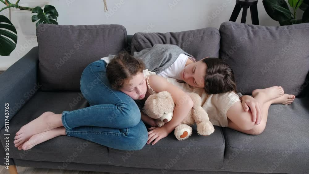 Calm cute little girl with beautiful young mother lying together resting on cozy sofa, mom embarrassing kid daughter cuddling enjoying healthy daytime nap at home, mommy and child relaxing on couch Calm cute little girl with beautiful young mother lying together resting on cozy sofa, mom embarrassing kid daughter cuddling enjoying healthy daytime nap at home, mommy and child relaxing on couch