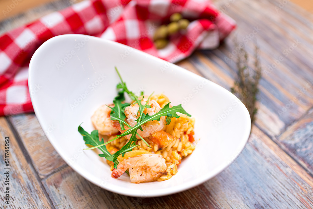 A portion of risotto with shrimp, seafood and arugula in a deep boat plate A portion of risotto with shrimp, seafood and arugula in a deep boat plate