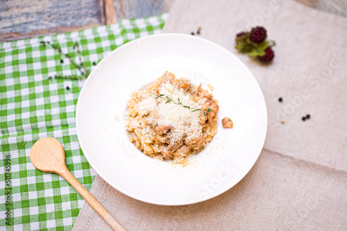 a portion of risotto with seafood and parmesan cheese grated on top. one plate on the table top view.