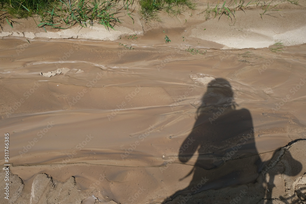 Shadow of a photographer with a bicycle on the erosion of clay soil ...