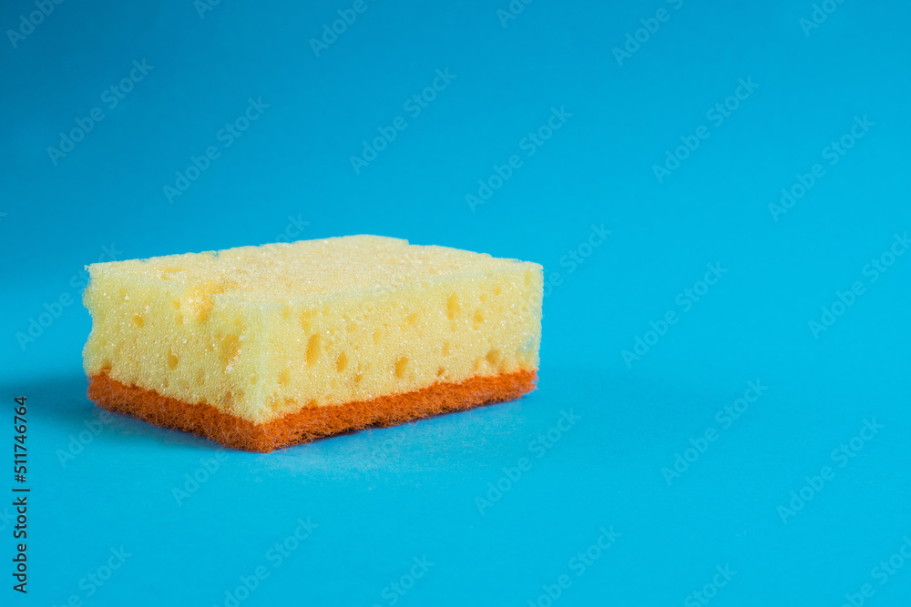 Porous sponge for washing dishes and cleaning in the apartment on a blue background. The concept of using environmentally friendly detergents for the home