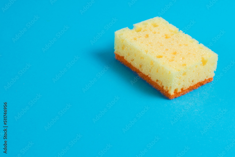 Yellow porous sponge for cleaning on a blue background with copy space. Home cleaning concept Yellow porous sponge for cleaning on a blue background with copy space. Home cleaning concept