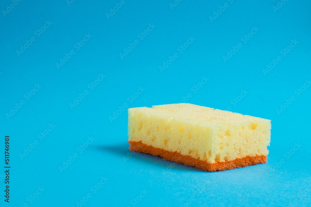 Yellow porous sponge for cleaning on a blue background with copy space. Home cleaning concept