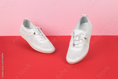 Levitating women's white summer boots on a two-tone red background.