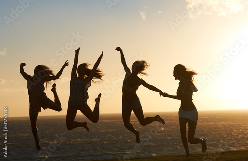 Feeling on top of the world. Silhouette of a group of girlfriends on the beach having lots of fun jumping around.