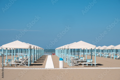 Fototapeta Naklejka Na Ścianę i Meble -  Blue and white beach cabanas lined up and ready for the day's beachgoers in Viareggio, Italy.