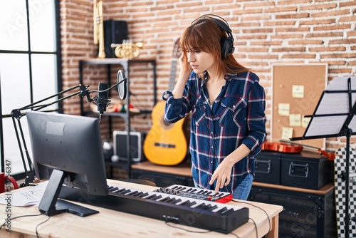 Young woman musician playing piano keyboard at music studio