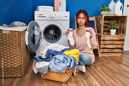 Young caucasian woman doing laundry holding socks depressed and worry for distress, crying angry and afraid. sad expression.